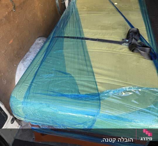 מזרן עטוף בניילון כחול בתוך רכב הובלה